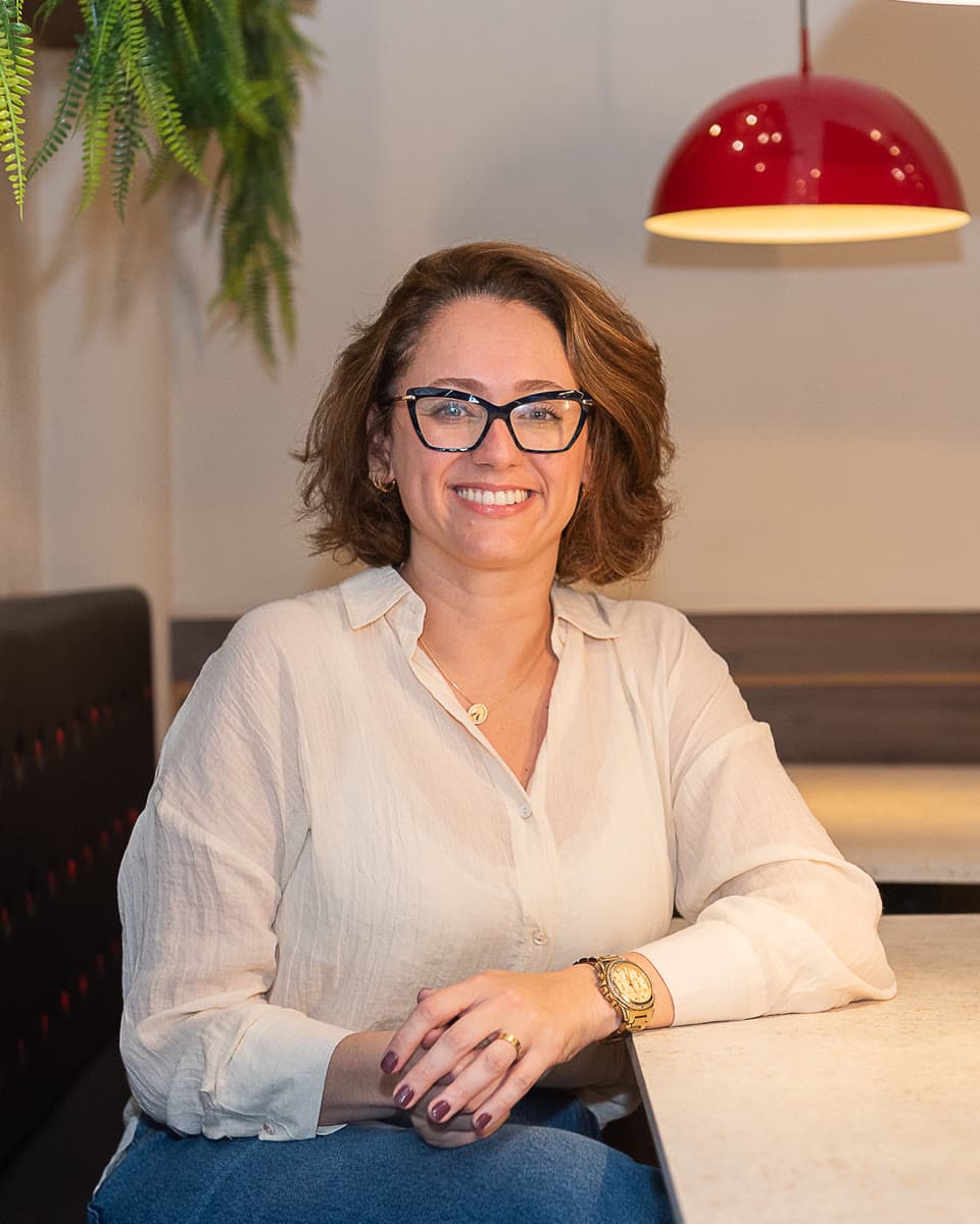 Gabi, fundadora e CEO da StartRH, sorri sentada à mesa