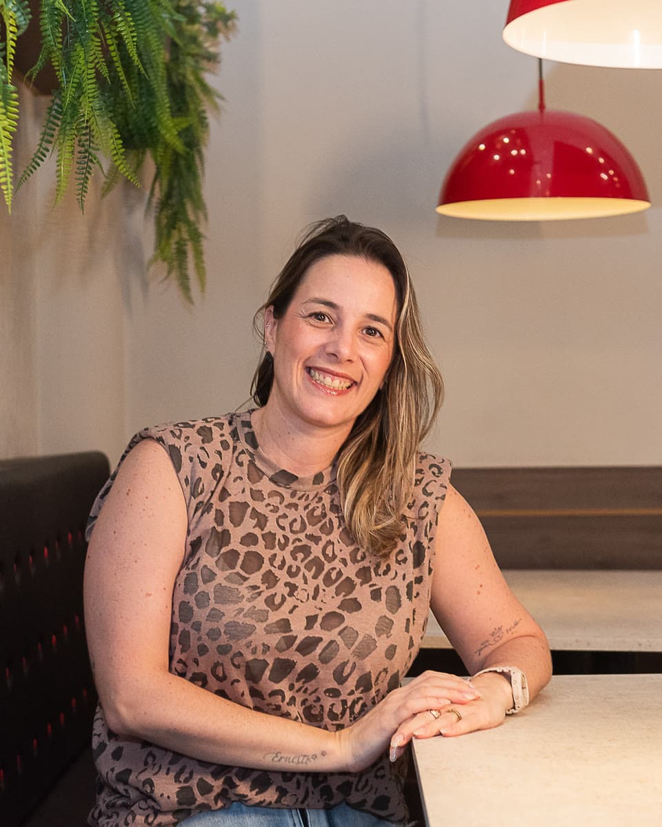 Ingrid, líder de operações de recrutamento, sorri sentada à mesa